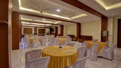 A banquet hall with round tables and decorative ceiling lights at VITS Lonavala.