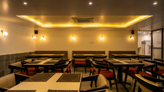 A well-lit, spacious dining hall at VITS Select, Bengaluru, featuring neatly arranged rows of tables and chairs under soft illumination - one of the best restaurants in Hebbal