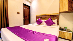 Deluxe Room king bed with purple accent runner, wooden headboard and AC unit at VITS Select Kharadi Pune