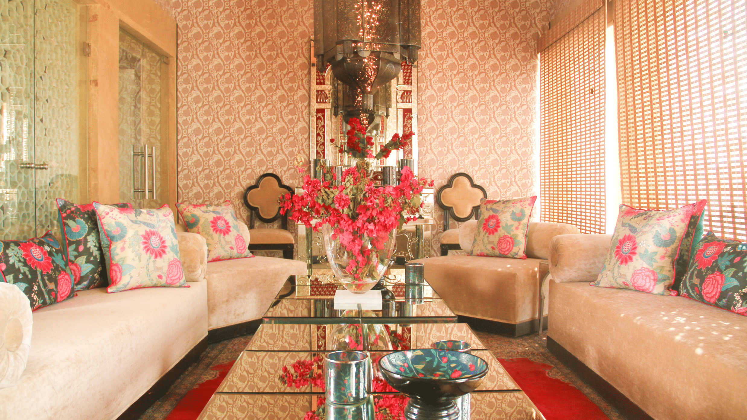 A luxurious seating area featuring sofa set in a U shaped setting, elegantly designed cushions, and table at the centre where flower vase and decorative bowls ae placed - Sonaar Haveli, Jaisalmer