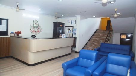 Reception at Hotel Srinivas, Kochi with a sitting area featuring blue sofas and wall arts.