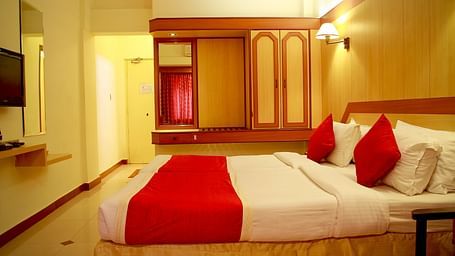 a view of a room furnished with a comfortable bed, television, wardrobe and looking glass - Hotel Swagath, Bangalore