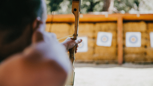 A person is aiming an arrow at a target with a bow.