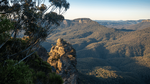A scenic overlook with a rocky outcropping in the foreground and a vast valley of rolling hills in the distance.