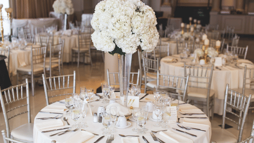Banquet hall set up for an event, featuring round tables with white tablecloths and silverware.