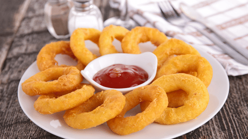 onion rings kept on a plate with ketchup in the centre