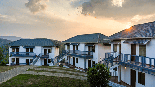 Two-storey Valley View Rooms with grey roofs and blue balconies at sunset at Abad Silvermist, one of the top Vagamon resorts with pool.