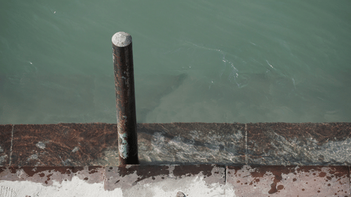 A close-up view of a metal post on a stone ledge overlooking a calm body of water at Ananta Express, Katra.
