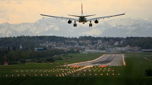 An aeroplane landing on a runway with grass on either side of it