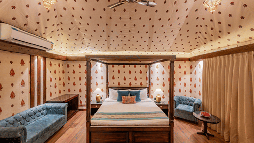 A premium tent with a cosy bed , flanked by pendent lantern lights on the sides  at Ananta Spa And Resort, Pushkar