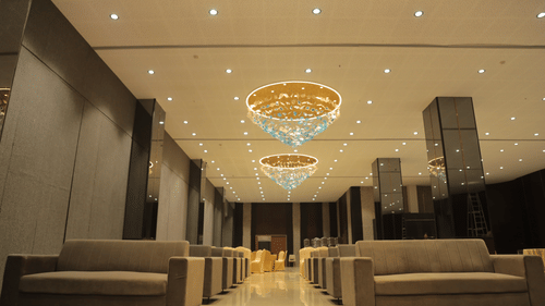 A grand hotel lobby or hall with plush sofas and large chandeliers reflecting in the ceiling - Biznotel By Pride Surat