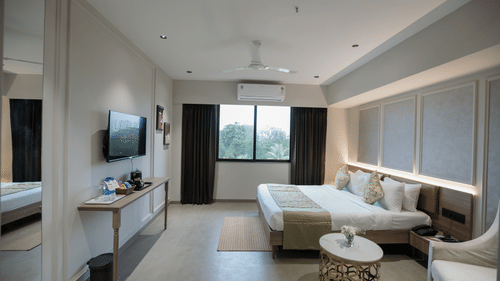 A spacious suite room with a comfy sofa, flat-screen TV, and large windows offering natural light - Biznotel By Pride Surat