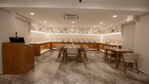 A dining area featuring a buffet setup and tables with chairs, designed for casual meals - Biznotel By Pride Surat