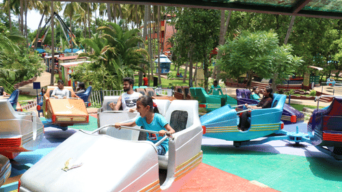 An overview of the Break Dance ride with individuals sitting in their seats - Black Thunder, Coimbatore