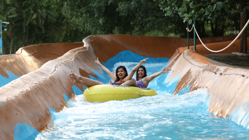 A slide full of water with two women sliding down in a tube - The Black Thunder
