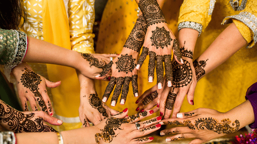 A close-up shot of several women's hands decorated with elaborate and intricate henna patterns.