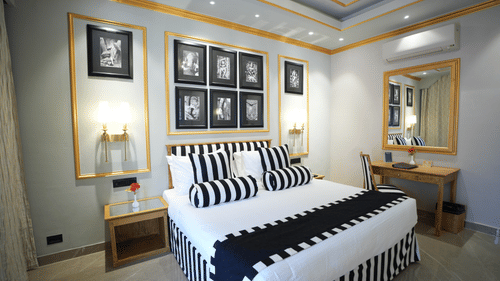 An Executive Suite bedroom at Clarks Khajuraho with a neatly made bed, patterned bedding, framed artwork above the headboard, and side lamps.