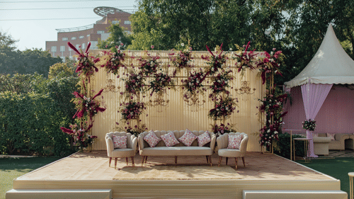 Beautiful outdoor wedding stage featuring elegant seating, vibrant floral decorations, hanging chandeliers, and a stylish backdrop, designed for memorable wedding ceremonies and celebrations.