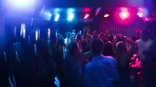 A blurry image of a crowded dance floor with blue and red lights