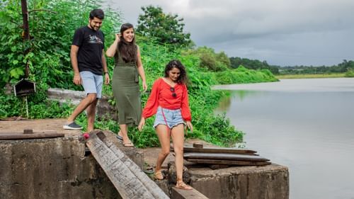 2 women and 1 man walking on a makeshift bridge with a lake on the right hand side - Heritage Village Resort & Spa, Goa