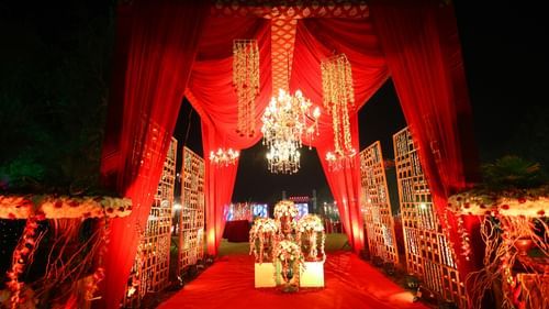 a wedding venue decked up with red cloth and chandelier in the backdrop of the night
