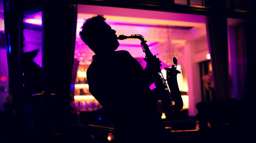 Silhouette of a musician performing indoors, set against vibrant lighting .