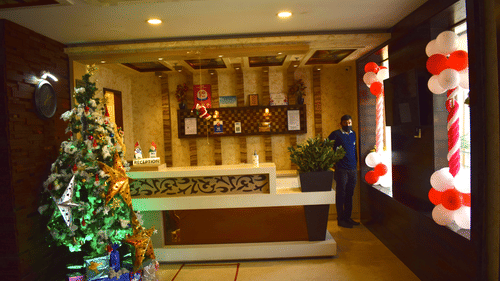 The reception area at Hotel Uday Palace features a desk with a Christmas tree to the side, and balloons added to the windows.