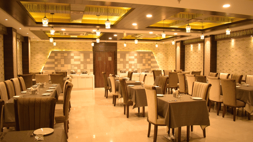 A modern and elegantly designed dining area with neatly arranged tables and warm lighting, showcasing a fine restaurant in Varanasi - Hotel Uday Palace.