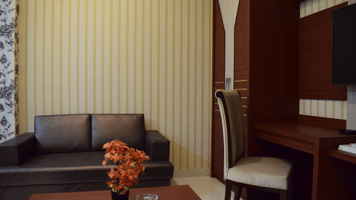 A cozy and well-furnished hotel room with sofa seating, study desk, and elegant decor, ideal for those looking for the best place to stay in Varanasi with family.