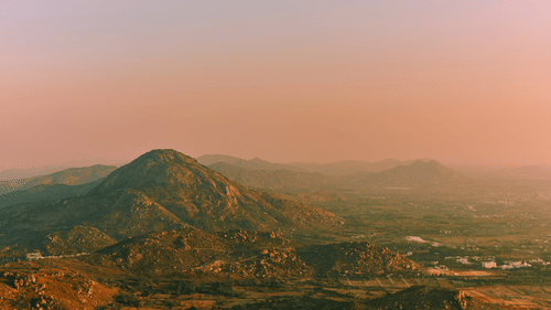 Panoramic view of towering mountains from a hilltop, highlighting the stunning natural scenery and peaceful surroundings.