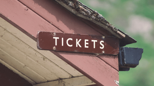 Wooden sign displaying tickets at a park entrance.
