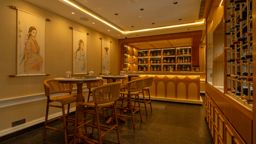 Elegant interiors of VietNom restaurant featuring warm lighting, wooden seating, a stylish bar, and an extensive wine display | Kenilworth Hotel, Kolkata