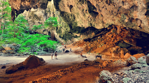 people standing under a natural rock cave