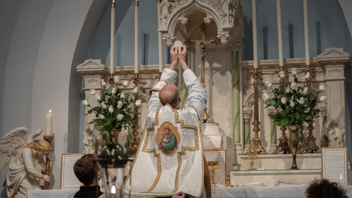 A priest performing rituals during a midnight mass inside a church with altar boys behind him