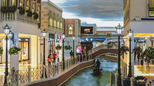 An indoor shopping centre designed like Venice, featuring a canal with a gondola, stone bridges, and street lamps.