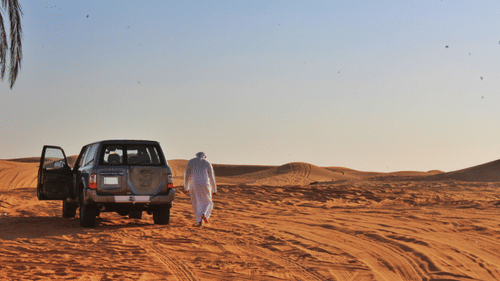 An overview of a desert with a car and a person next to the vehicle in view.
