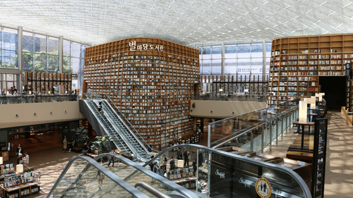 An overview of a mall as seen from the first floor with the escalator and shops in view.