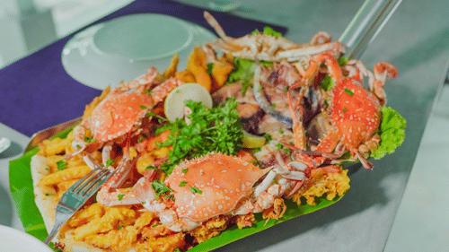 A large platter of mixed seafood, including crabs and shrimp, with some vegetables, served on a green tray.