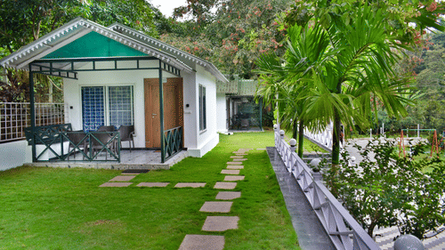 A cottage style building in the MGM Whispering Winds (Resorts) with a grassy lawn with trees in the front.