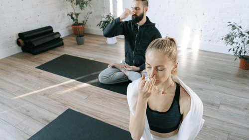 Two individuals performing yoga together on a yoga mat.