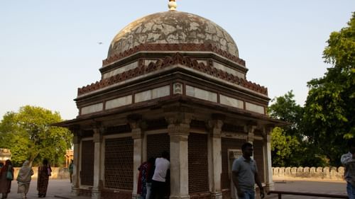 A historic domed tomb set amidst lush greenery, showcasing classic Indian architecture.