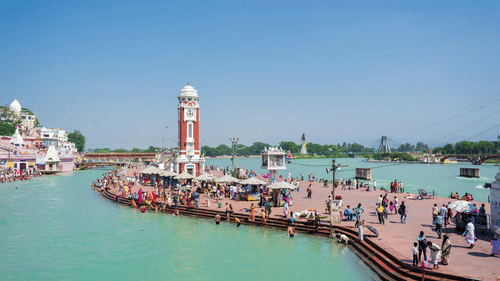 An overview of a lighthouse in Haridwar with people thronging towards the waterbody.