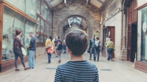 a child looking at people standing and speaking to each other inside a museum.
