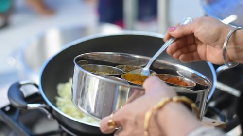 A woman using assorted spices bowl to add in the dish. 