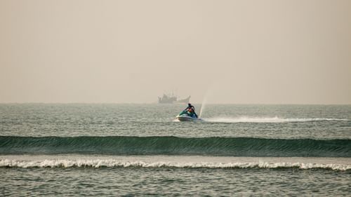 Jet ski rider gliding over ocean waves against a hazy sky backdrop.