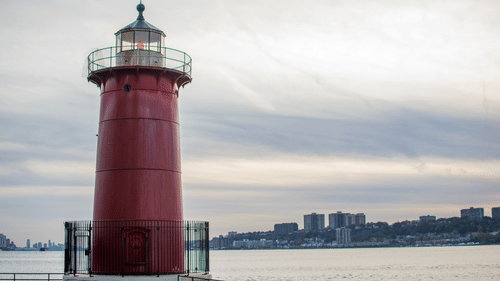 a red lighthouse on the banks of a lake