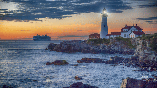 A lighthouse near a beach with a sunset in the background