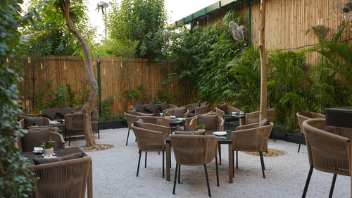 Nemesia's outdoor dining area is surrounded by plants and trees.