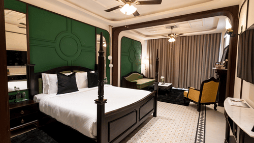 An image of a bedroom with king size bed, flat TV screen, chair, and sofa - Polo Cherrapunjee Resort