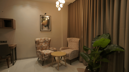 Suite Room living area with sofa chairs and a chandelier - Pride Elite, Dwarka